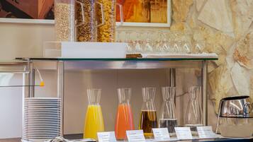 A breakfast bar with various food and drink options, including cereal, juices, and a coffee pot.