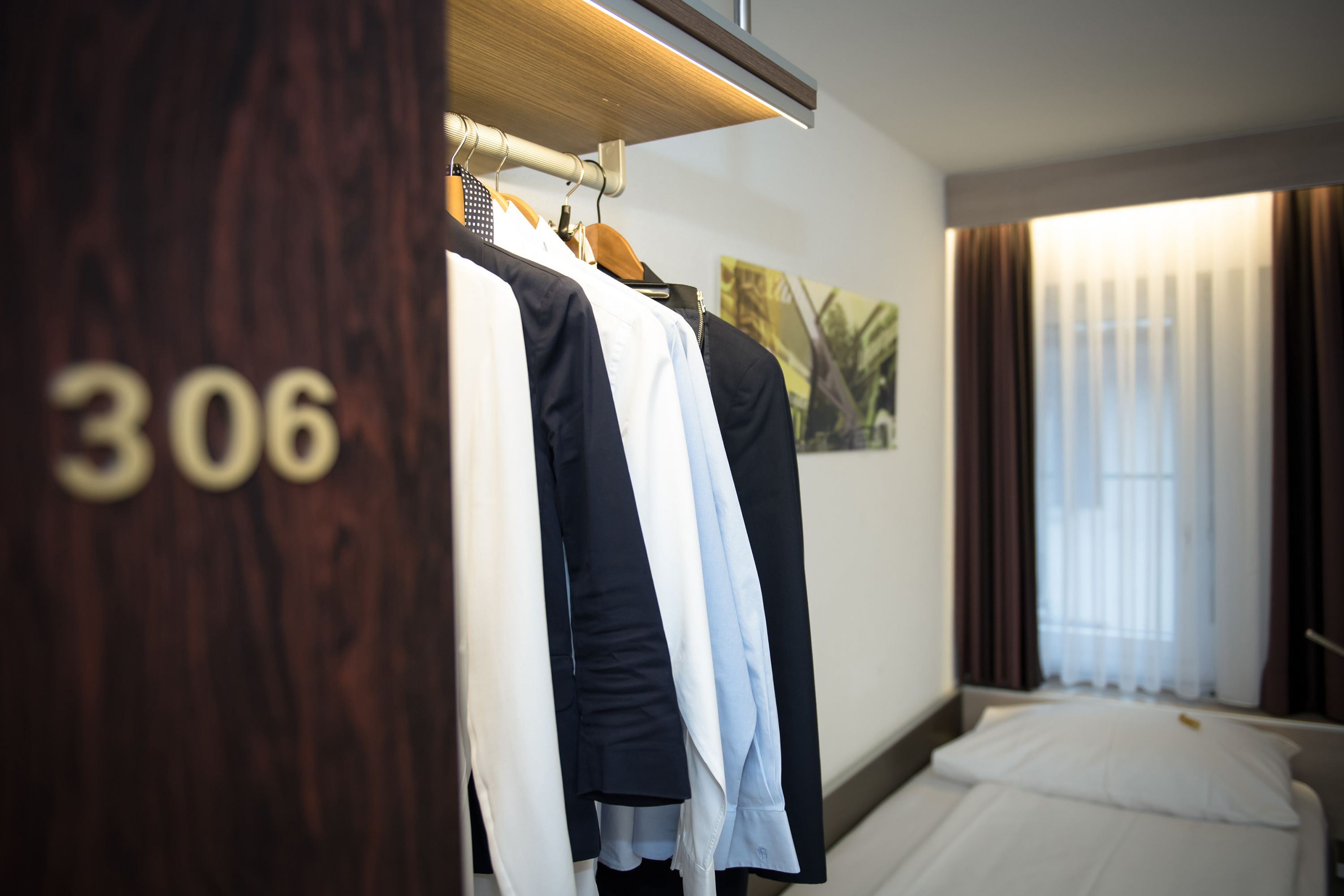 Ein Hotelzimmer mit Bett, einer Kleiderschrank mit Kleidung und einem Bild an der Wand.