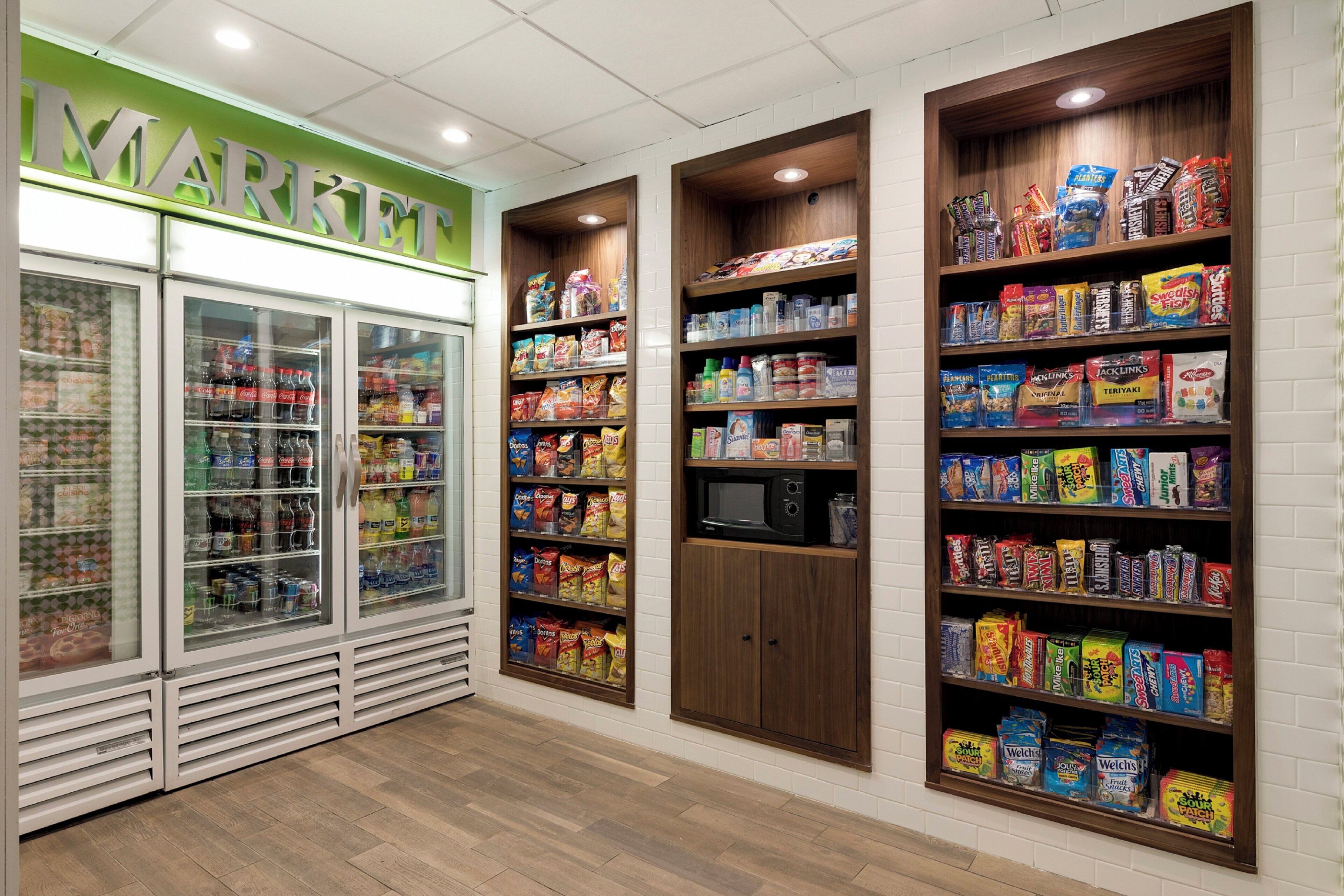 Een supermarktinterieur met koelvitrines, snackrijen en een magnetron.