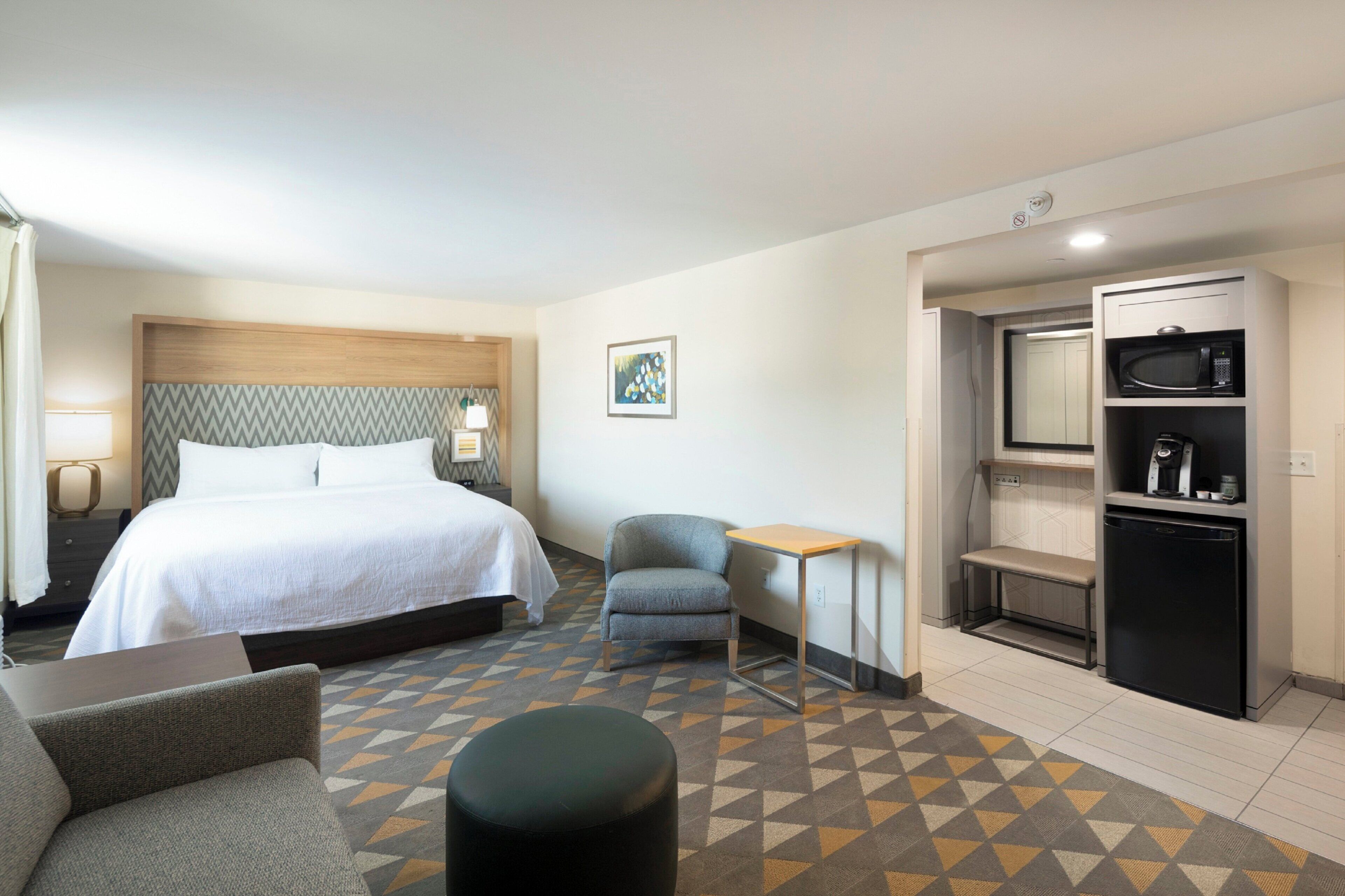 Une chambre d’hôtel équipée d’un lit, d’une chaise, d’une petite table, d’un four à micro-ondes et d’un réfrigérateur.