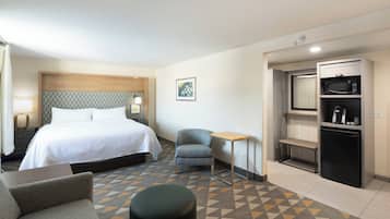 Une chambre d’hôtel équipée d’un lit, d’une chaise, d’une petite table, d’un four à micro-ondes et d’un réfrigérateur.
