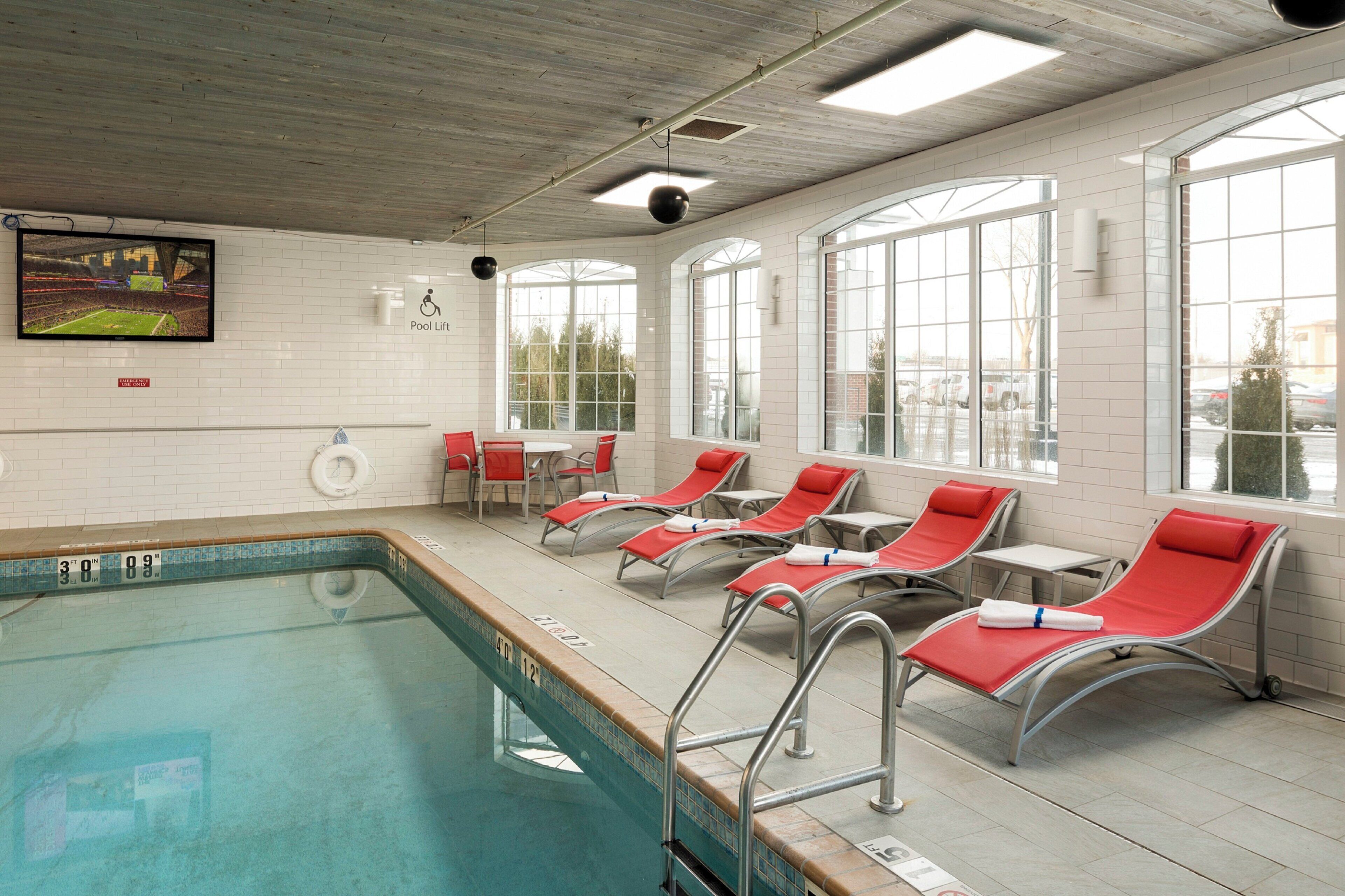 Ein Schwimmbeckenbereich mit Liegestühlen und einem großen Fenster.
