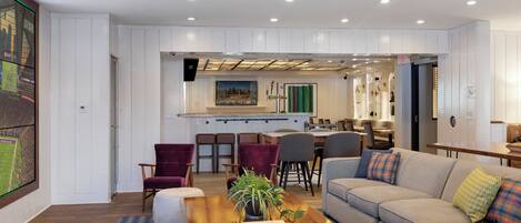 Una sala de estar moderna con un sofá, sillas, una mesa de centro y un televisor instalado en la pared.