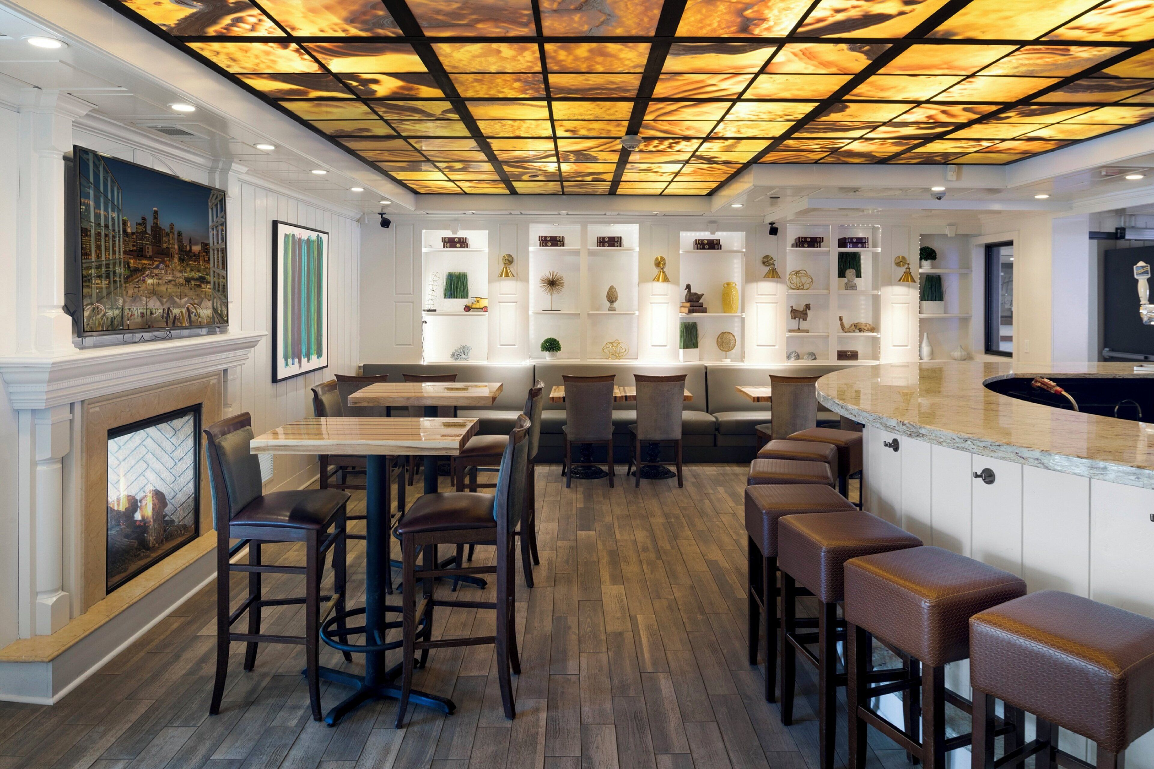 Ein Restaurantinneres mit hohen Decken, Holzboden und einer Bar mit Hockern.