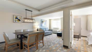 A hotel room with a dining area, a sofa, and a view of the outside.