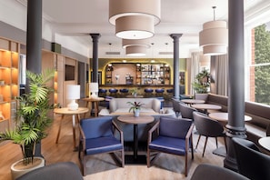 A modern lounge area with seating arrangements, a bar, and a large window providing a view.