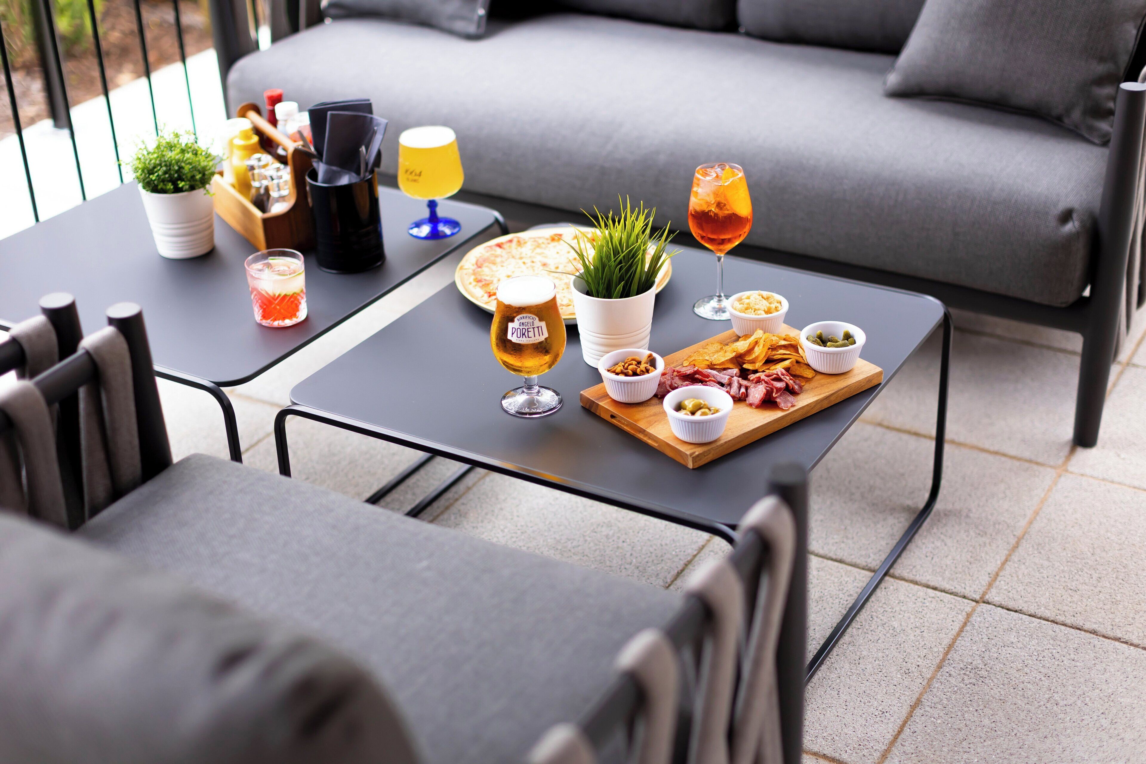 A dining area with a table set for two, featuring a pizza, drinks, and snacks.