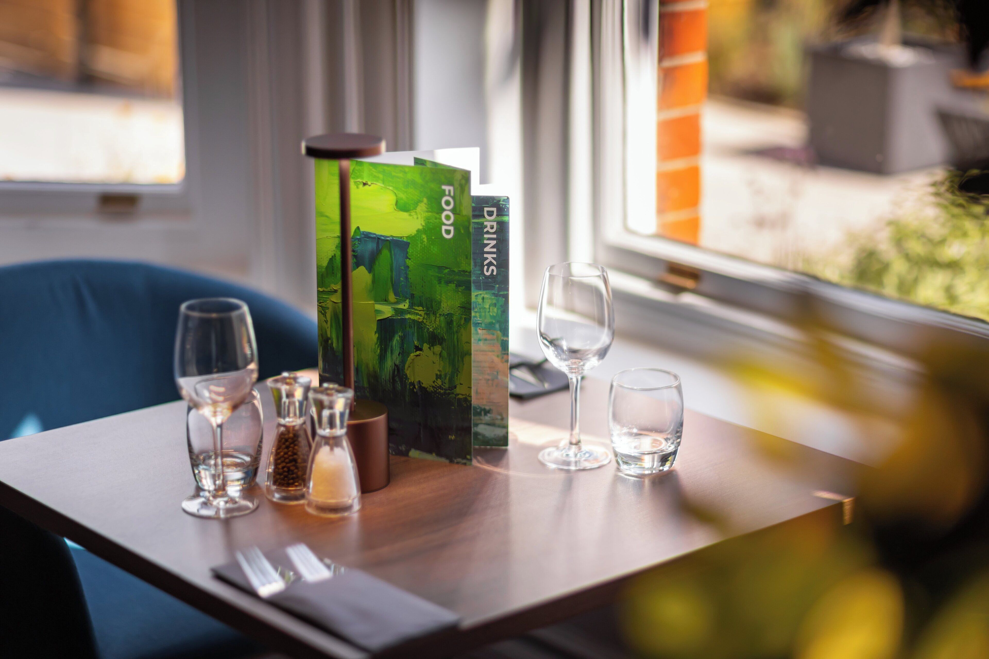 Una mesa con una copa de vino, una botella pequeña y un menú.