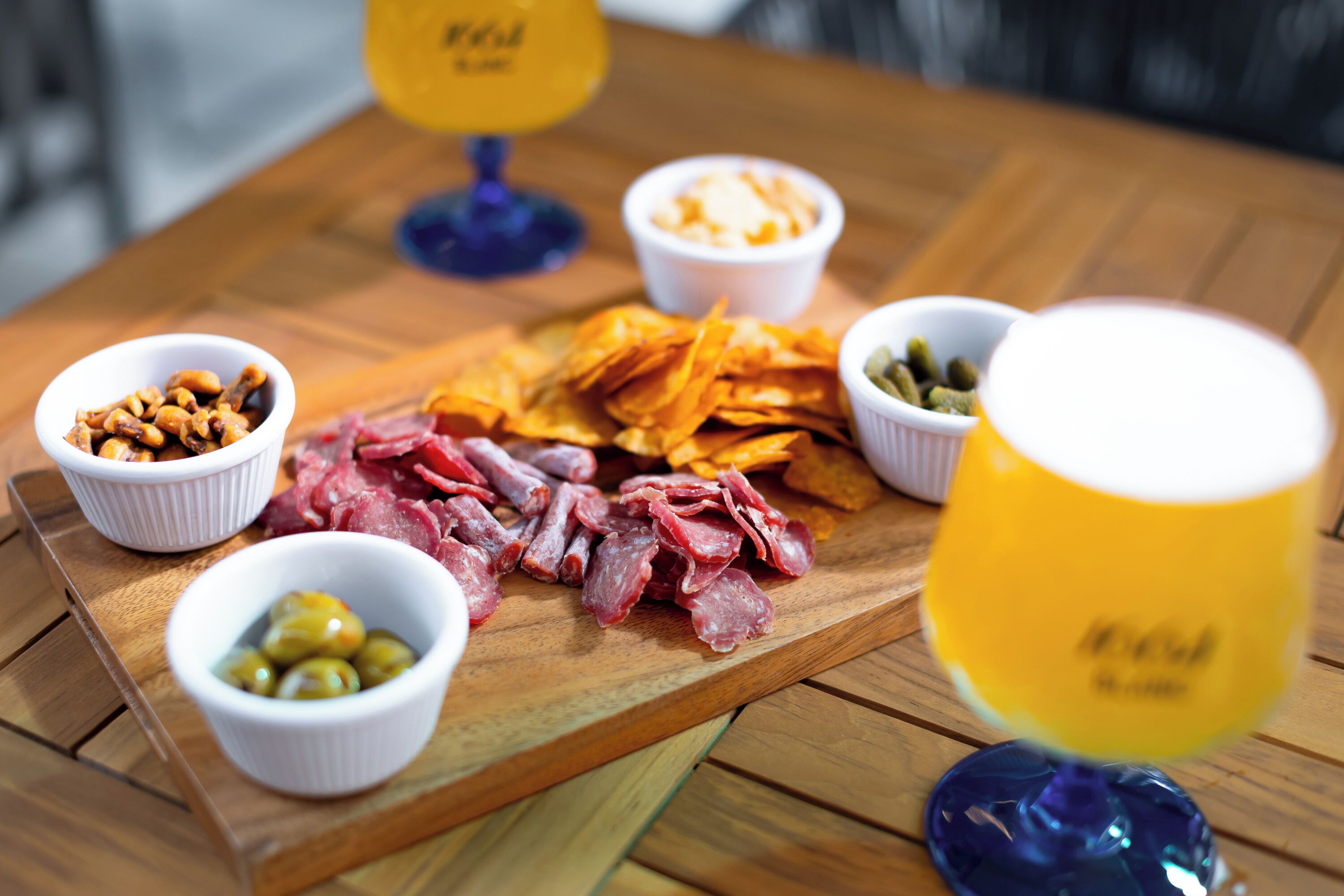 A wooden table with various food items and a glass of beer.