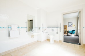 A modern bathroom with a large mirror, a sink, and a toilet.