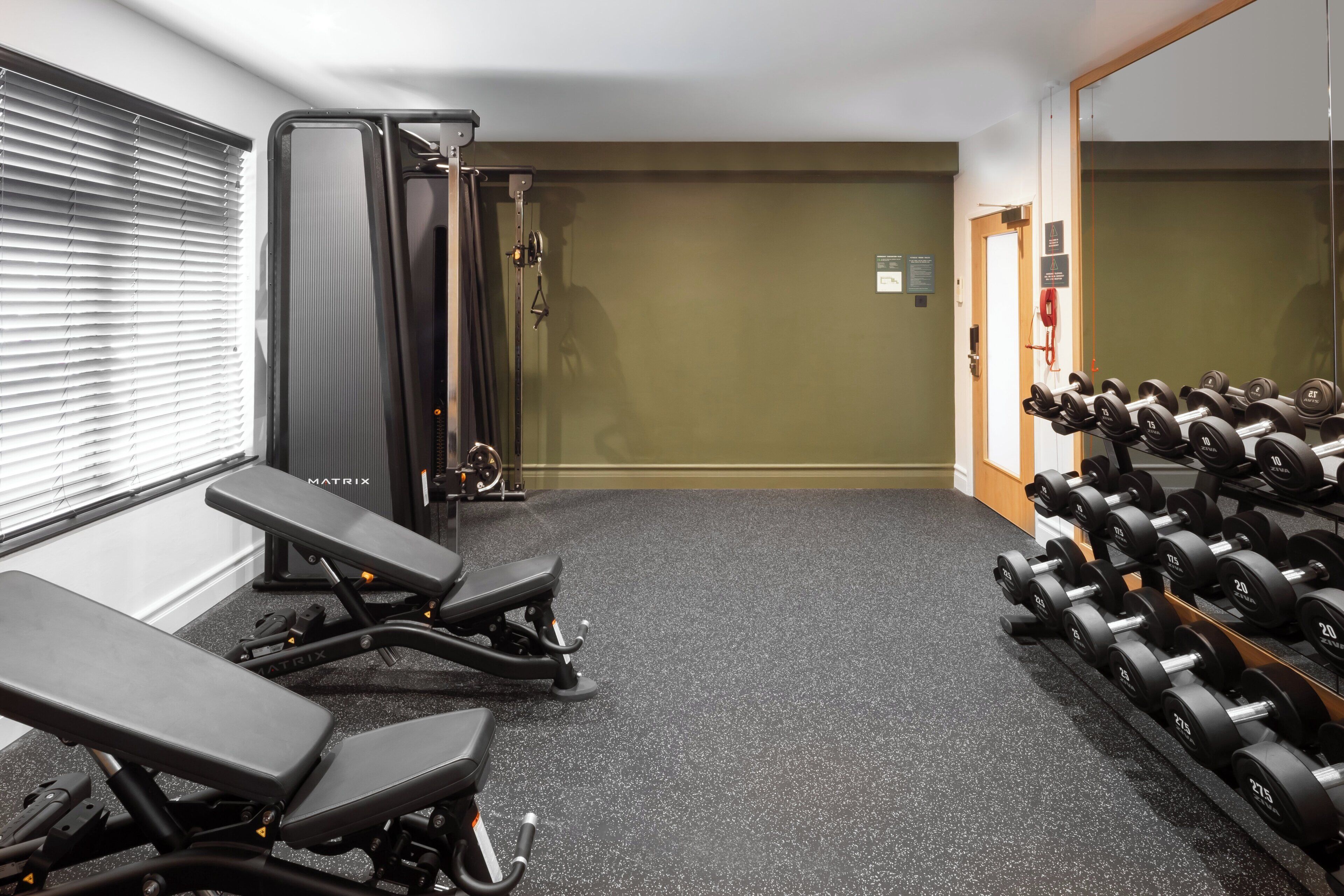 Uma academia com equipamentos de exercícios, um banco e uma barra com halteres.