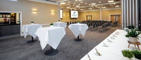 A conference room with tables set for a meeting, a bar area, and a projection screen in the background.