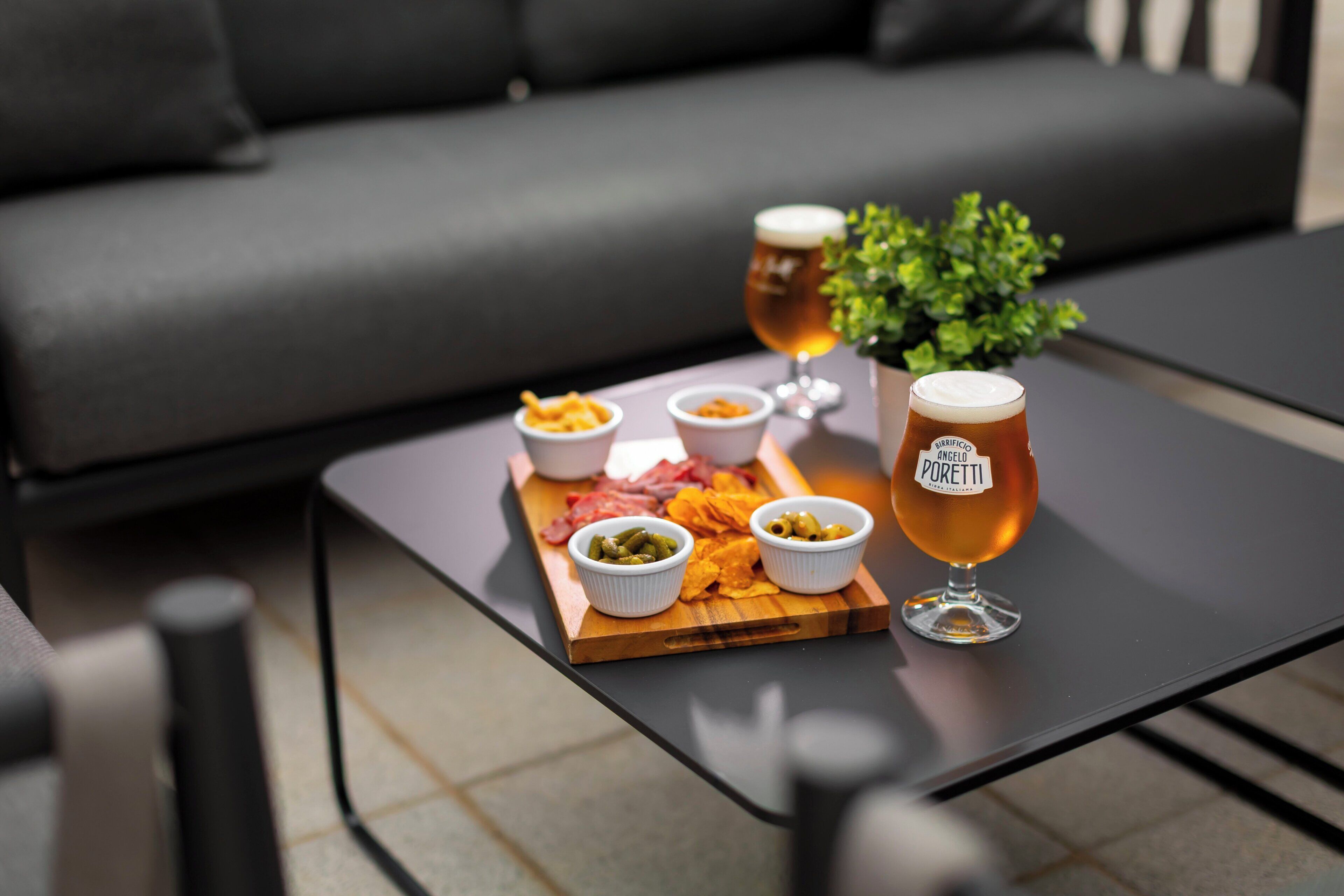 Una mesa con una bandeja de aperitivos y dos vasos de cerveza.