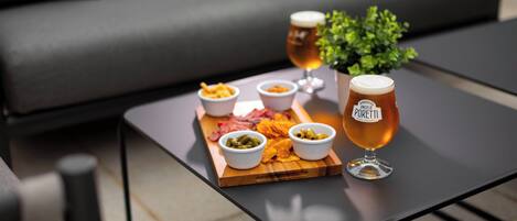 Una mesa con una bandeja de aperitivos y dos vasos de cerveza.