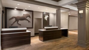 A reception area with two reception desks, a large wall-mounted horse sculpture, and a modern light fixture. - Holiday Inn Saratoga Springs by IHG (Saratoga Springs)