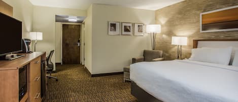 Een hotelkamer met een groot bed, een bureau met een computer, een stoel en een televisie.