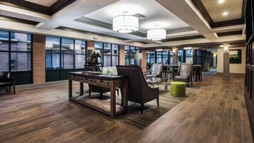 A spacious hotel lobby with a large desk, leather chairs, and a green ottoman.