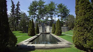 A formal garden with a central water feature, trimmed hedges, and tall trees. - Holiday Inn Saratoga Springs by IHG (Saratoga Springs)
