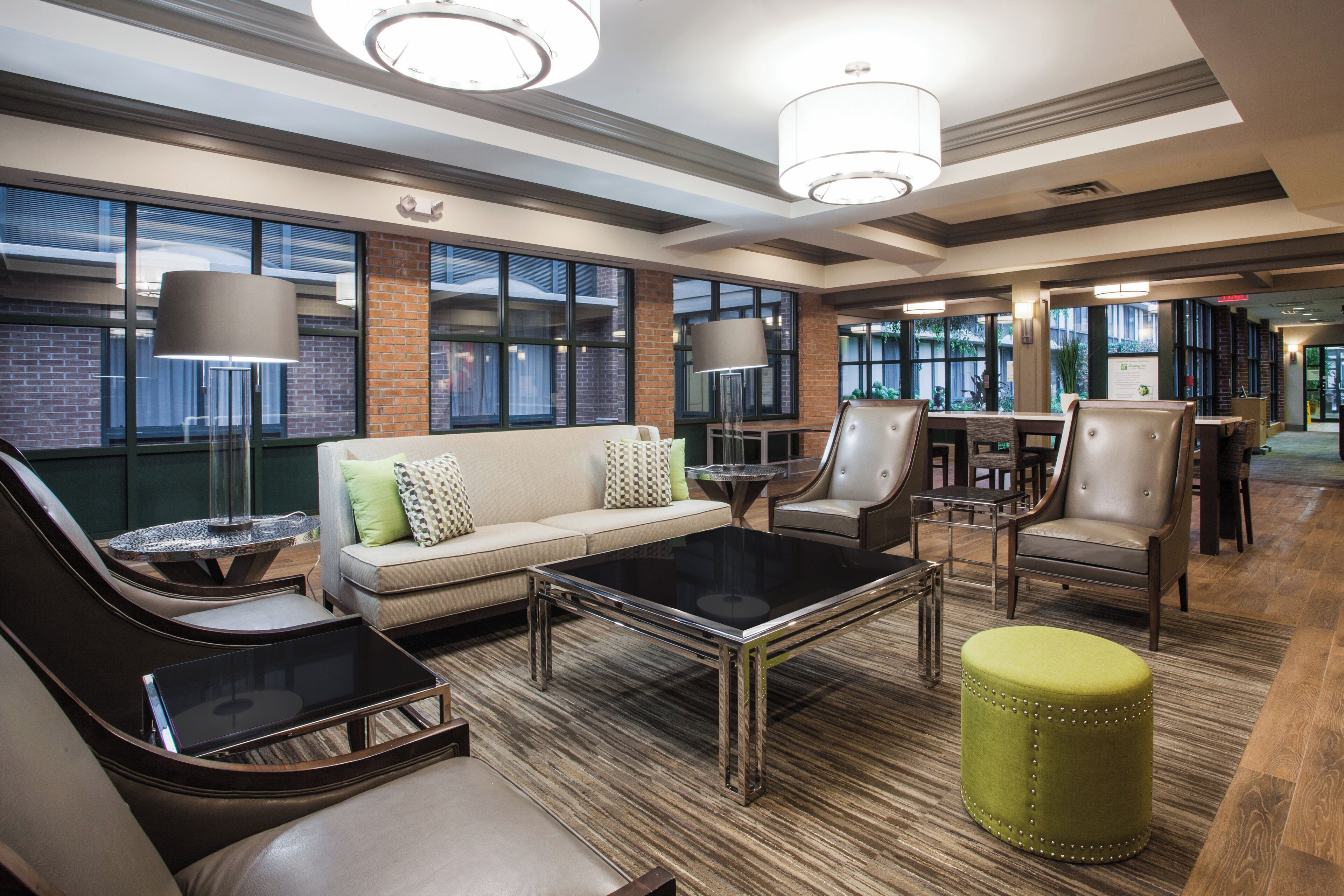 A modern lounge area with leather sofas, a glass coffee table, and a green ottoman.