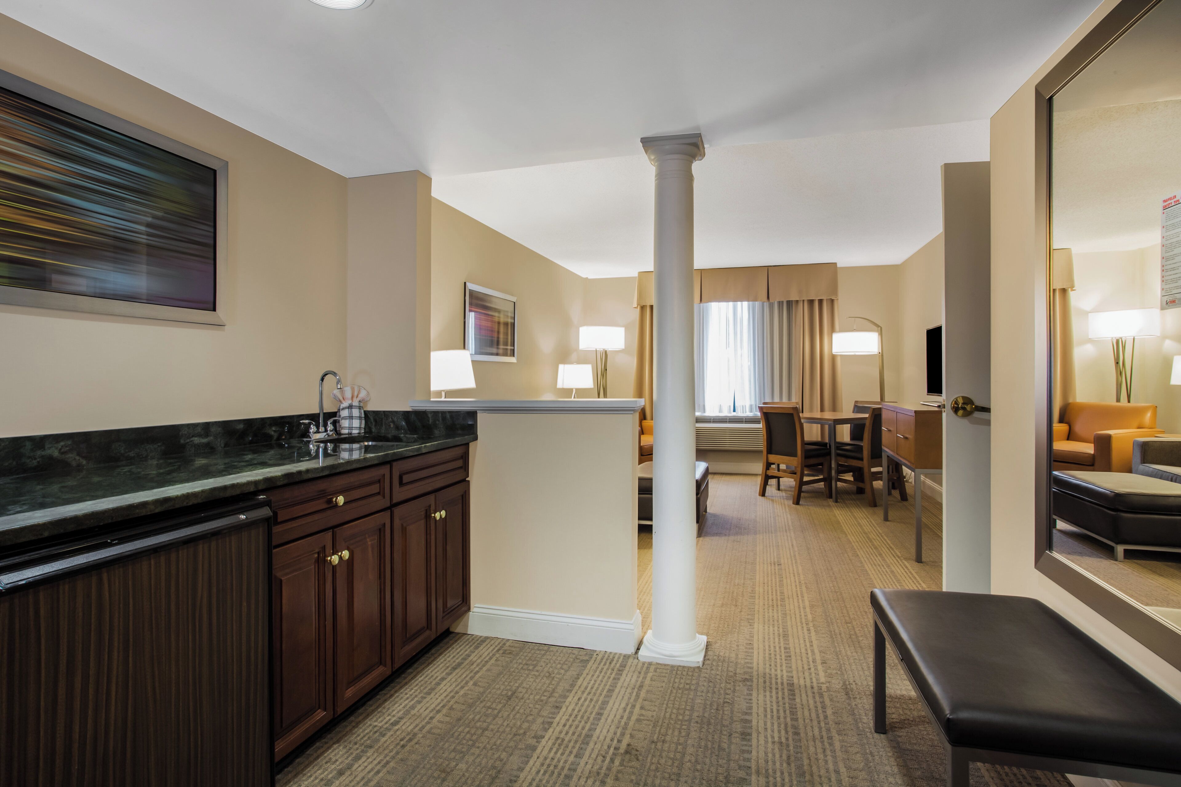 Une chambre d’hôtel équipée d’un coin cuisine, d’une table à manger et d’un espace salon avec un banc.