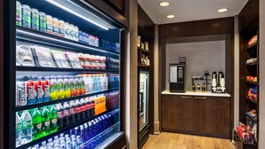 Habitación de hotel con minibar repleto de bebidas y aperitivos, una cafetera y un pequeño rincón con asientos.