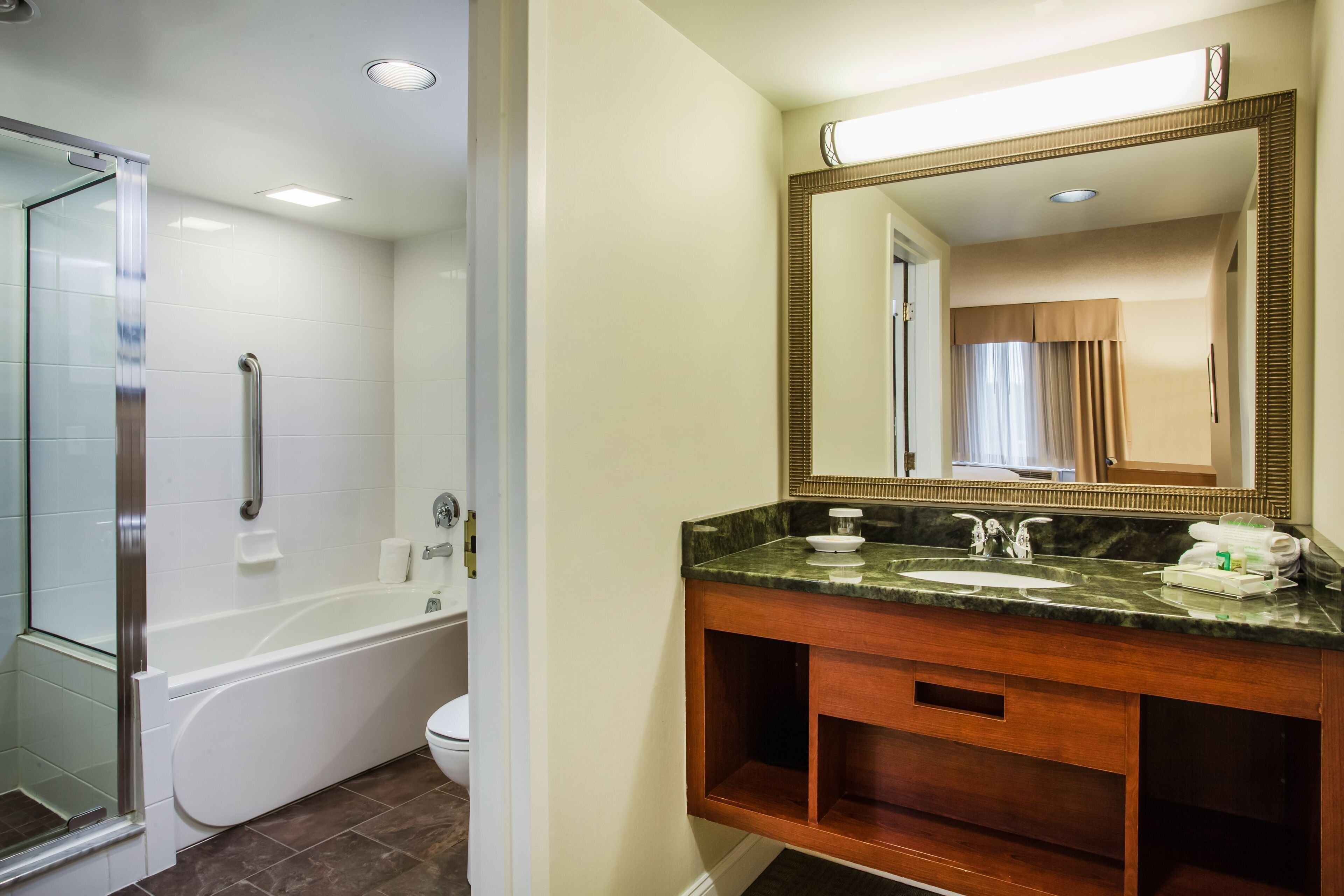 A bathroom with a bathtub, a sink with a mirror, and a shower area.