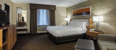 A hotel room with a bed, a desk, a TV, a chair, and a sofa.