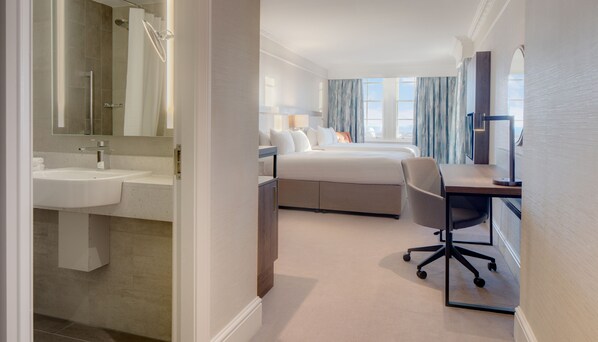 A hotel room with a bathroom, a bed, a desk, and a chair.