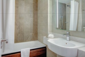 A bathroom with a bathtub, a sink, and a mirror.