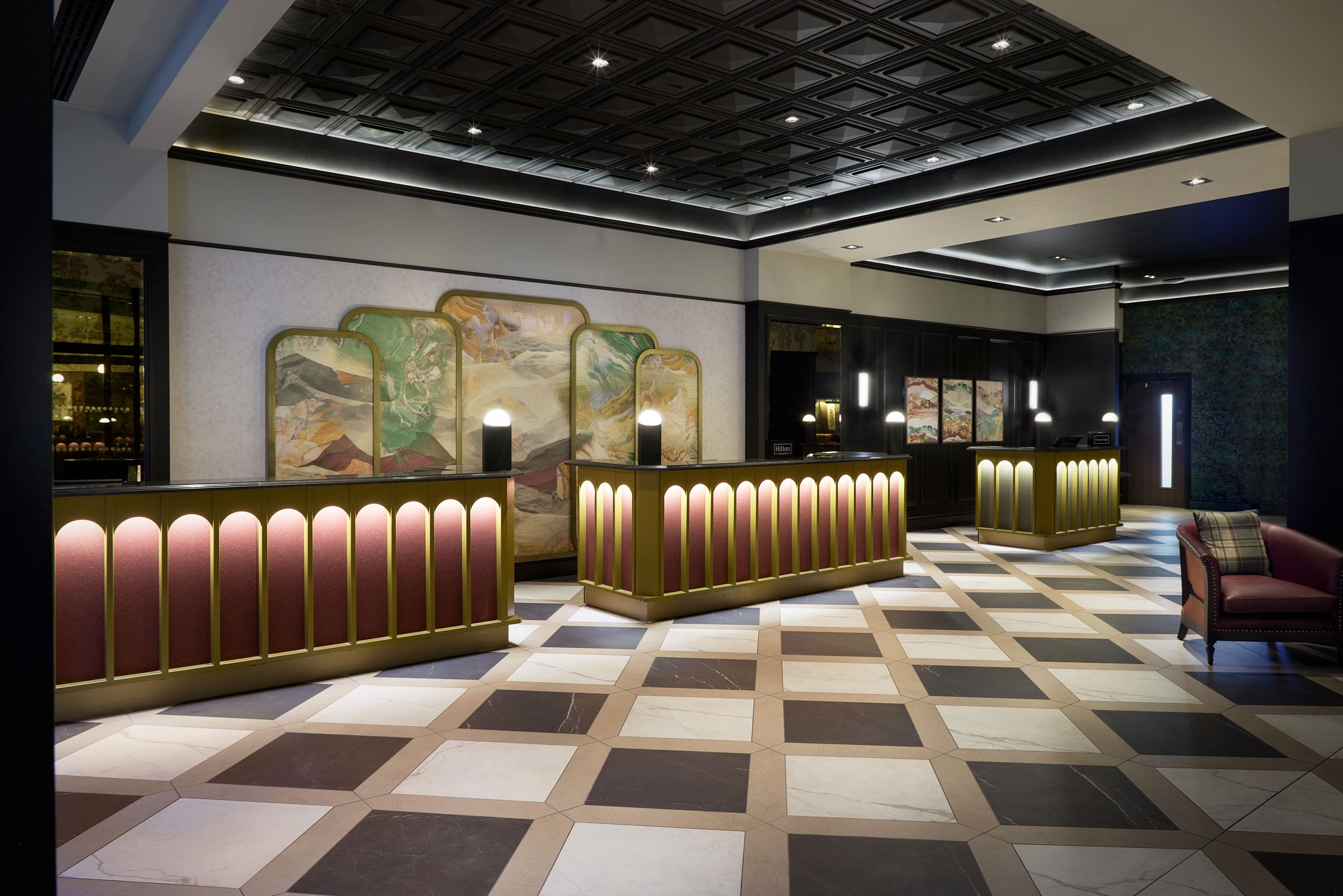 Un vestíbulo de hotel con mostrador de recepción, área de espera y asientos.