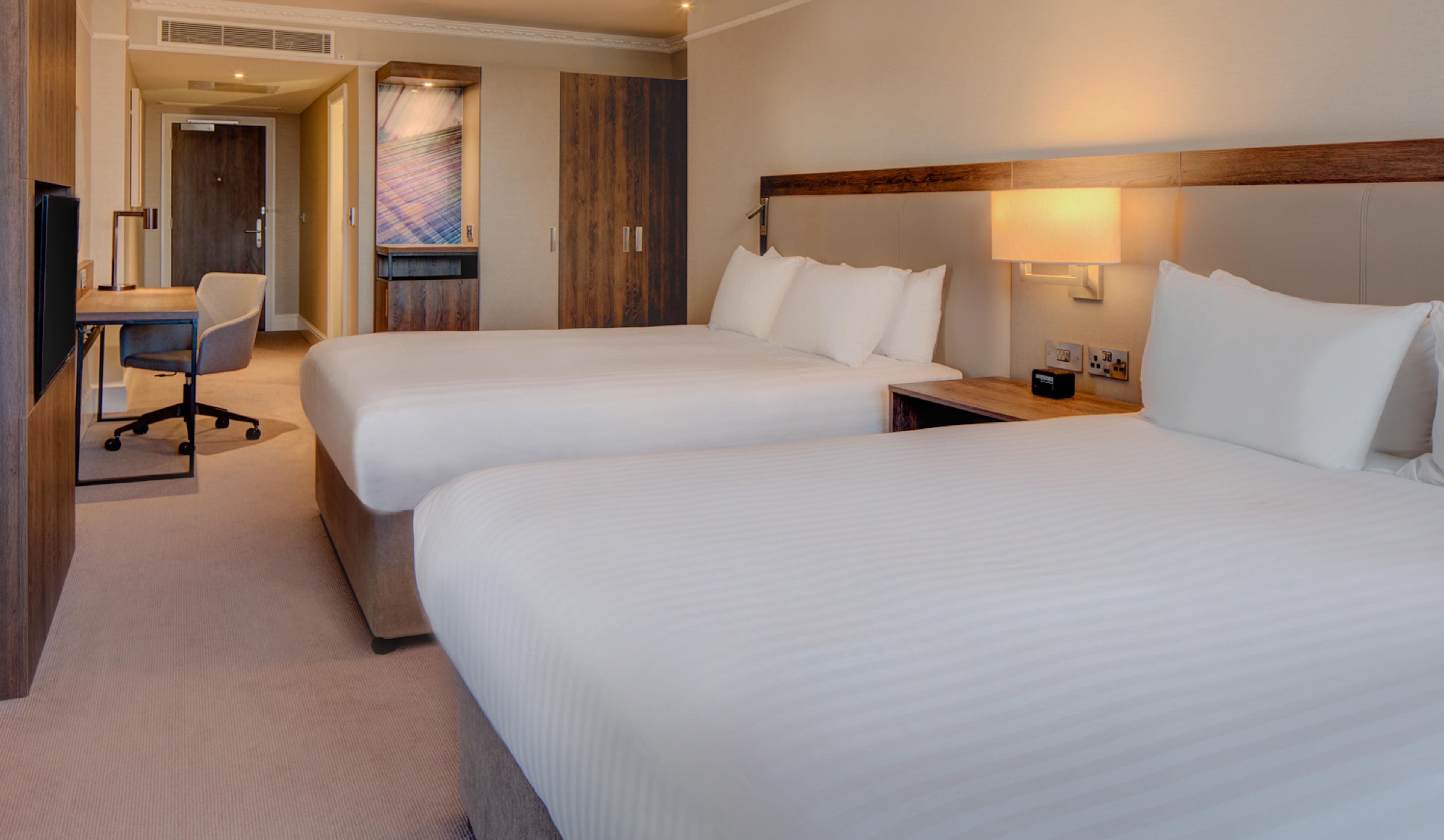 Ein Hotelzimmer mit zwei Betten, einem Schreibtisch und einem Stuhl.