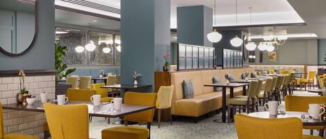 A restaurant with yellow chairs, tables, and a blue wall.
