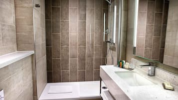 Un baño moderno con cabina de ducha de vidrio, bañera y tocador con lavamanos y espejo.