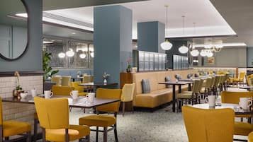 A restaurant with yellow chairs, tables, and a blue wall.
