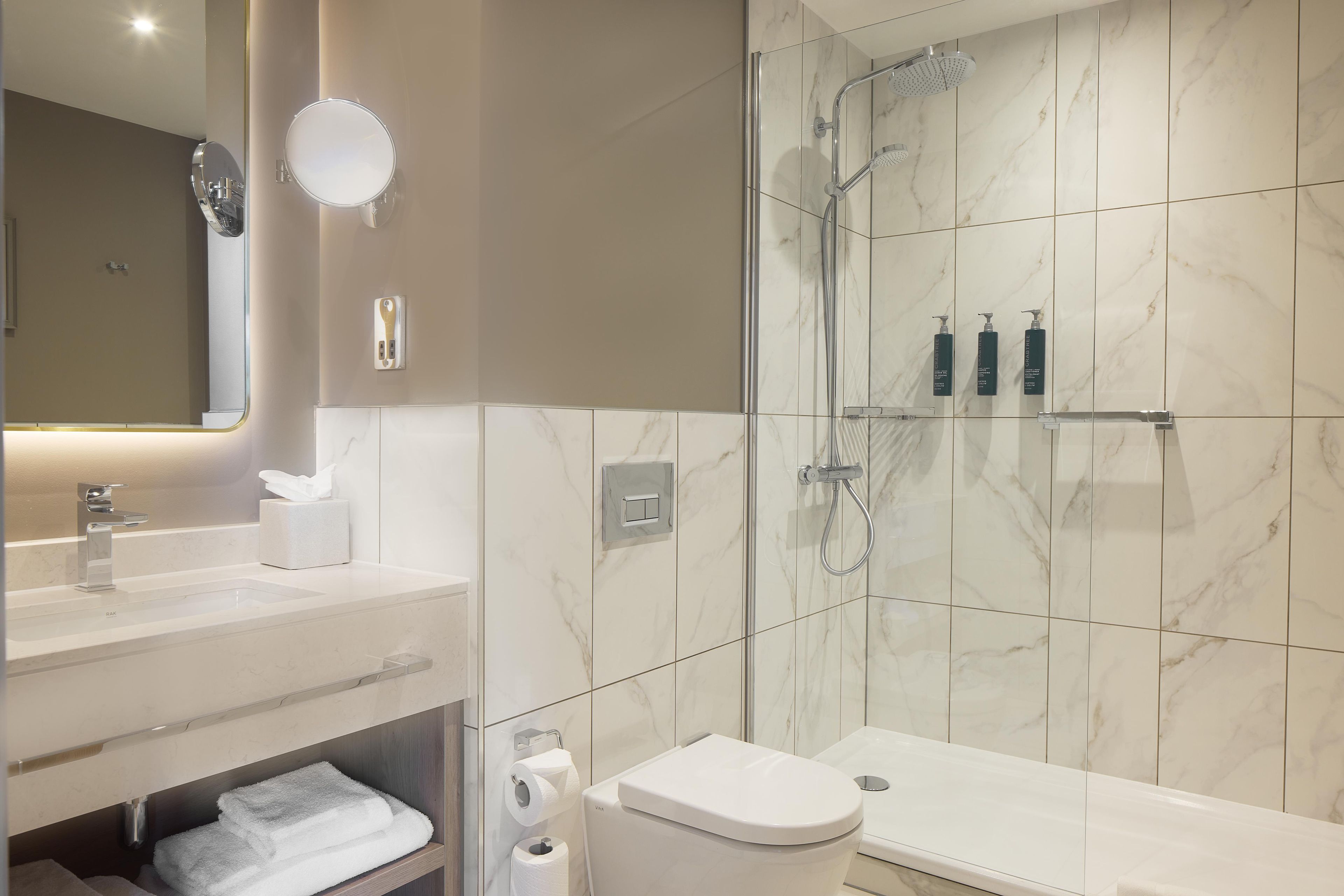 A modern bathroom with a glass-enclosed shower, a vanity with a mirror, and a toilet.