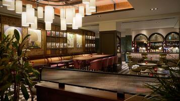 A bar area with seating, a checkered floor, and a ceiling with hanging lights.
