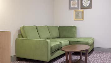 Un sofá verde, una mesita de madera y una obra de arte botánica enmarcada en la pared.