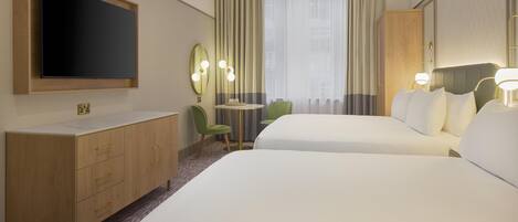 A hotel room with a TV, a desk with a chair, two beds, and a large window with curtains.