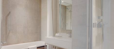 A modern bathroom with a bathtub, a glass-enclosed shower, and a vanity with a mirror.
