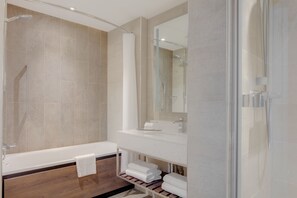 A modern bathroom with a bathtub, a glass-enclosed shower, and a vanity with a mirror.