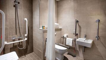 A modern bathroom with a shower, toilet, sink, and grab bars.