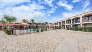 A hotel with multiple balconies, a swimming pool, and a gravel courtyard. - Days Inn by Wyndham San Antonio Splashtown/ATT Center (San Antonio)