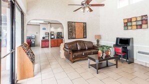 A spacious living room with a brown leather sofa, a coffee table, a TV, and a ceiling fan. - Days Inn by Wyndham San Antonio Splashtown/ATT Center (San Antonio)