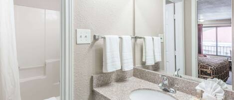 A bathroom with a granite countertop sink, a mirror, and a towel rack.