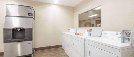 A laundry area with a stainless steel refrigerator and a Whirlpool washer.