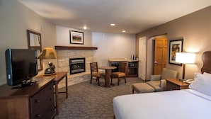 A hotel room with a bed, a television, a fireplace, a desk, and a chair. - HiMark (South Lake Tahoe)