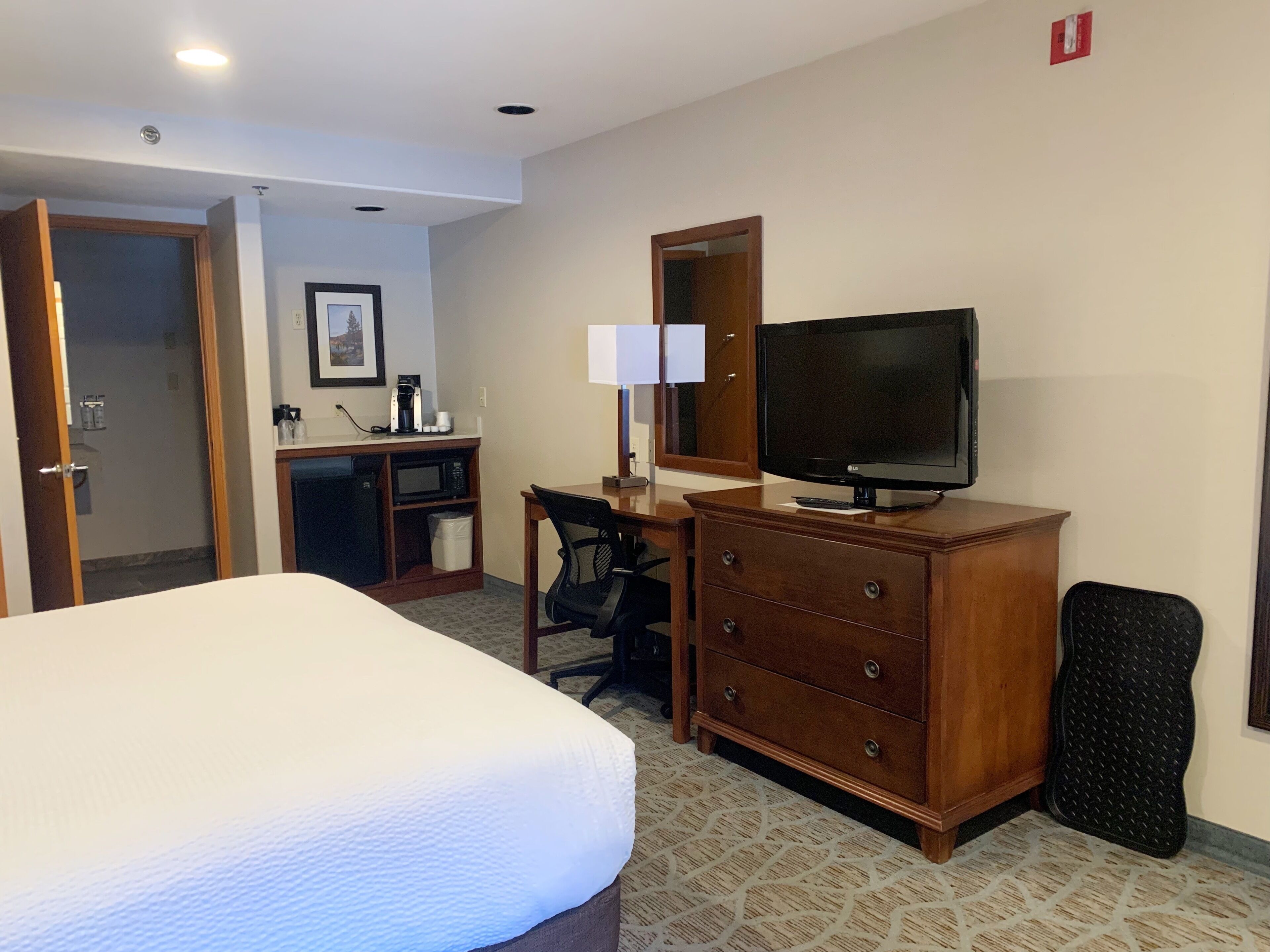 A hotel room with a bed, a desk with a computer, a television, and a dresser.