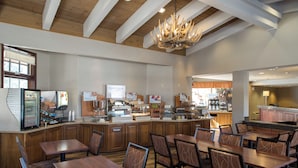 A restaurant with wooden tables and chairs, a bar area, and a chandelier. - HiMark (South Lake Tahoe)