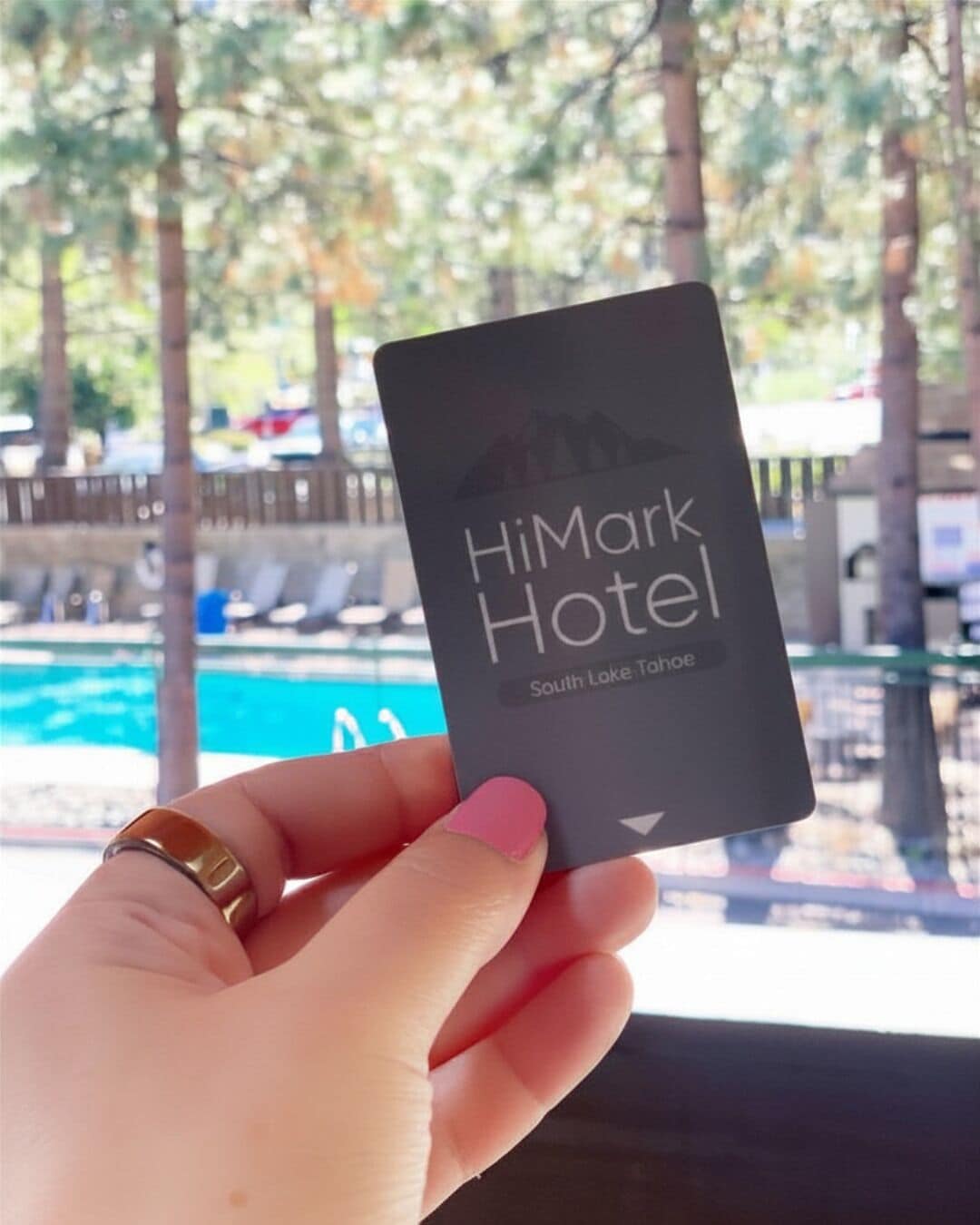 A hand holding a card with 'HiMark Hotel' and 'South Lake Tahoe' written on it.