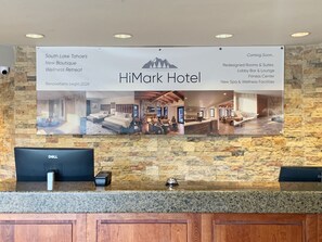 Ein Empfangstresen mit einem Banner, das den neuen Wellness-Kurzurlaub und die bevorstehenden Renovierungen des HiMark Hotels bewirbt.